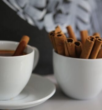 Taza de cafe con ramas de canela sobre la mesa