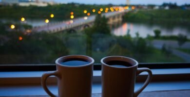 Dos tazas de cafe junto a una ventana