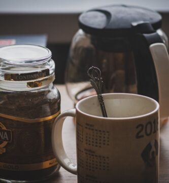 Tarro de vidrio con cafe instantaneo y una taza