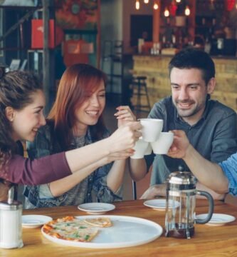 Grupo de amigos brindando con tazas de cafe en una cafeteria