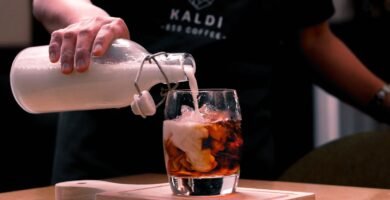 Barista vertiendo leche en un vaso de cafe helado