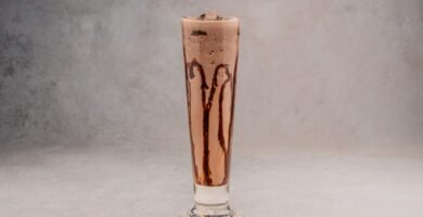 Malteada cremosa en vaso alto con chocolate escurriendo por el borde
