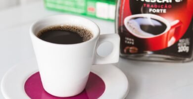 Taza de cafe negro junto a un tarro de cafe instantaneo