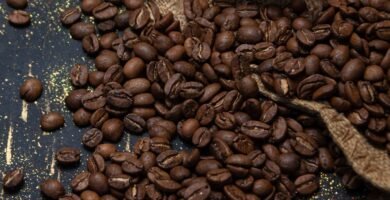 Granos de cafe tostado saliendo de un saco de yute