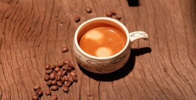 Taza de cafe y granos sobre una mesa de madera