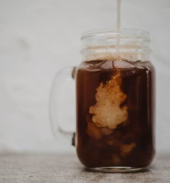 Cold brew coffee with cream swirling in a glass mason jar